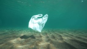 A plastic bag underwater drifts in the sea above a sandy bottom, Mediterranean, France