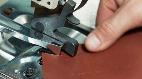 Craftsman using an automatic leather skiving machine. Skiving leather in a haberdashery manufactory. Splitting, aligning and cutting edge of leather details 4k
