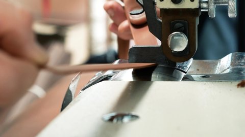 Craftsman using an automatic leather skiving machine. Skiving leather belt in a haberdashery manufactory. Splitting, aligning and cutting edge of leather details 4k
