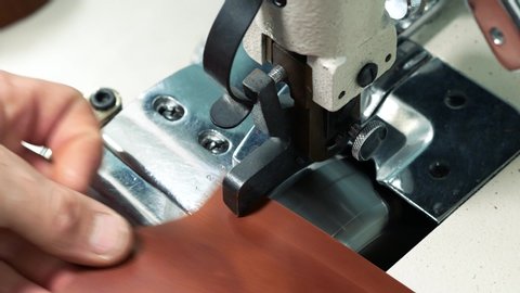 Worker using an automatic leather skiving machine. Skiving leather in a haberdashery manufactory. Splitting, aligning and cutting edge of leather details. Close up 4k