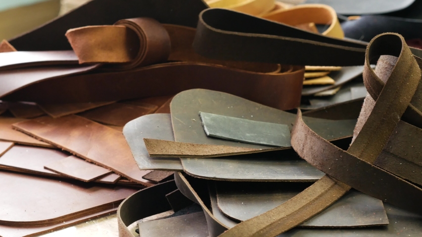 Leather waste. Flaps of cut leather on the table. Craftsman working area. Panoramic shot 4k Royalty-Free Stock Footage #1040085365