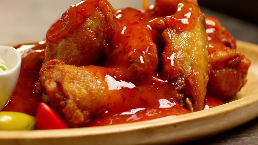 Bowl of buffalo wings with red and spicy sauce . Hot sauce pouring on chicken wings. Liquid pepper sauce pouring on chicken juicy meat into restaurant . Shot on RED Cinema camera in slow motion .   Royalty-Free Stock Footage #1040087603