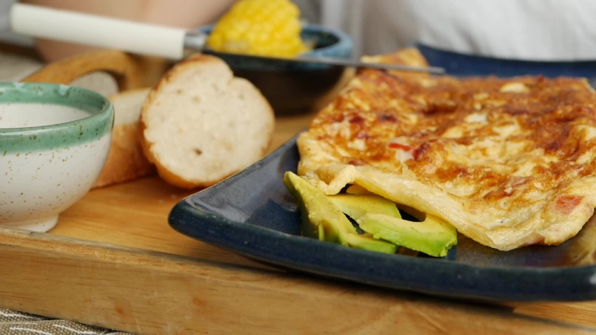 Someone eats omelet with vegetables, salad and avocado in restaurant. Scrambled eggs on a plate. Yummy. Close-Up
