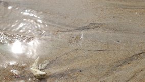 Close up water flow on soft sand with sunlight reflection