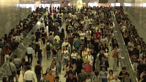 HONG KONG – 4 OCTOBER 2019: Commuting railway passengers use escalators and walkway in busy MTR (metro) station in downtown Hong Kong