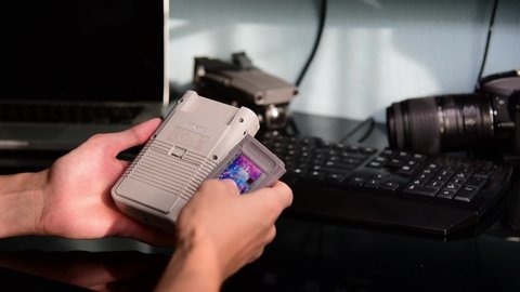 Kavala, Greece - 28 October, 2019: Man inserts a Tetris game cartridge into Nintendo Game Boy retro console and starts playing the game.