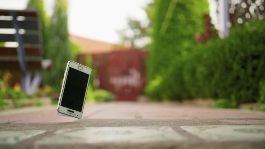 Mobile phone falls and breaks on the concrete ground in slow motion | Shutterstock HD Video #1040124716