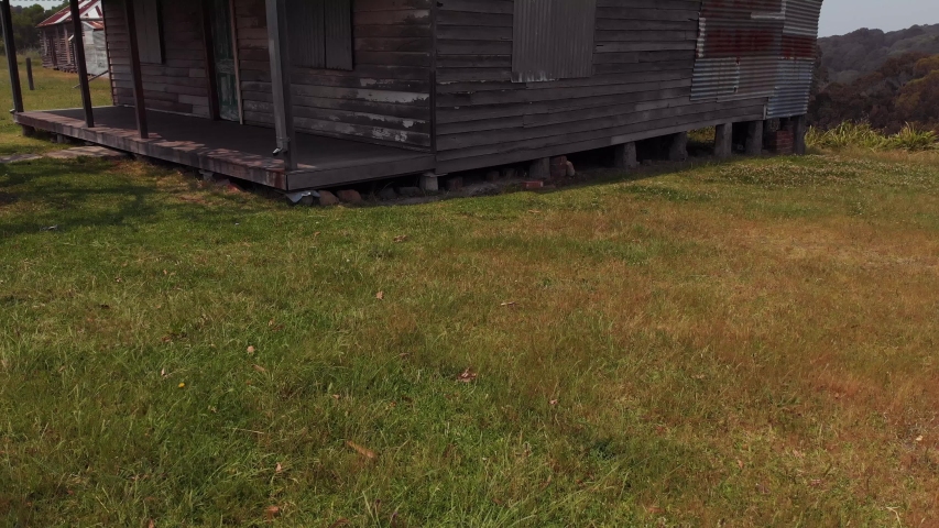Old House with a jacaranda tree over the roof, fly over with drone to back drop of trees and hills with dirt path.