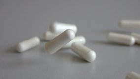 Tablets on a red background. Pills. Medicine and healthy. Close up of capsules. Many white medical capsules falling down on the red table. Slow motion. Closeup. - Powered by Shutterstock - Get 15% off with code: PIKWIZARD15