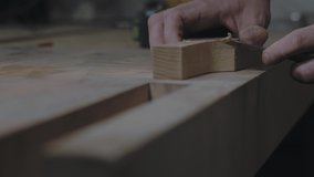 close-up of hands slicing a wooden product with a knife. a carpenter processes a wooden beam with a knife. 4k video. 59.94 fps