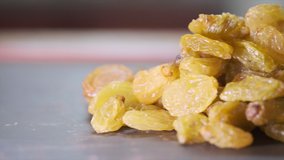 Yellow golden raisins on kitchen counter. Panning to the right. Selective focus. 