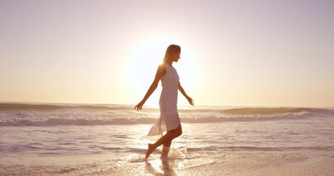 beautiful woman wearing white dress walking on beach at sunset in slow motion RED DRAGON