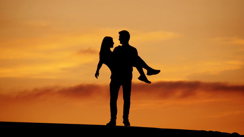 Similar to Happy couple dancing silhouettes against yellow sunset sky, tele...