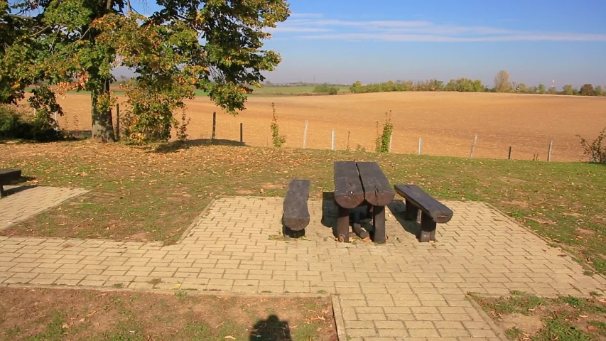 Wooden table and benches against a plowed field. Hungary