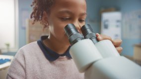 Portrait of Smart Little Schoolgirl Looking Under the Microscope. In Elementary School Classroom Cute Girl Uses Microscope. STEM (science, technology, engineering and mathematics) Education Program - Powered by Shutterstock - Get 15% off with code: PIKWIZARD15