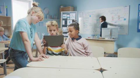 Elementary School Computer Science Class: Two Girls and A Boy Use Digital Tablet Computer with Augmented Reality Software, They’re Excited, Full of Wonder, Curiosity. Children in STEM