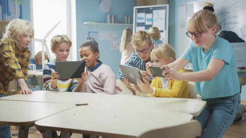 Elementary School Computer Science Class: Schoolchildren Use Digital Tablet Computers and Smartphones with Augmented Reality Software, They’re Excited, Full of Wonder, Curiosity. Children in STEM