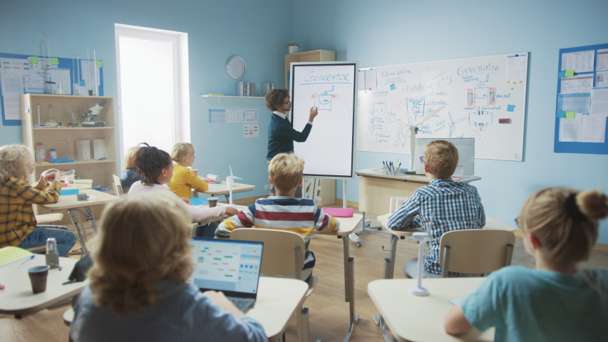 Elementary School Physics Teacher Uses Interactive Digital Whiteboard to Show to a Classroom full of Smart Diverse Children how Generator Works. Science Class with Curious Kids Listening Attentively Royalty-Free Stock Footage #1040164286