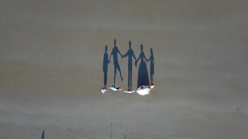 the flying camera shoots from top to bottom as the shadows of a family of 5 dance.