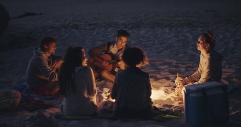Beach Party at sunset with bonfire and roasting marsh mellows with friends RED DRAGON