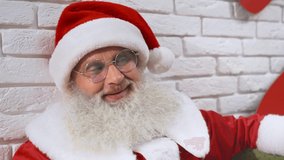 Cheerful authentic Santa Claus with real grey beard in glasses leaning on white wall and singing christmas carols. Senior man in red costume celebrating winter holidays. - Powered by Shutterstock - Get 15% off with code: PIKWIZARD15