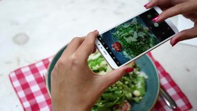 Closeup view of woman eating healthy vegetable salad in restaurant and making photos of it. Real time 4k video footage.