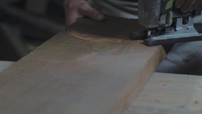 Close-up of electric jigsaw in action. Cutting board. Manufacturing of furniture. Man with electric jigsaw. 4k video. 59.94 fps