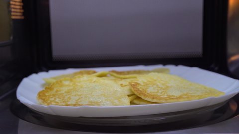 Cooking microwave food. Russian pancakes in bowl, microwave top view.