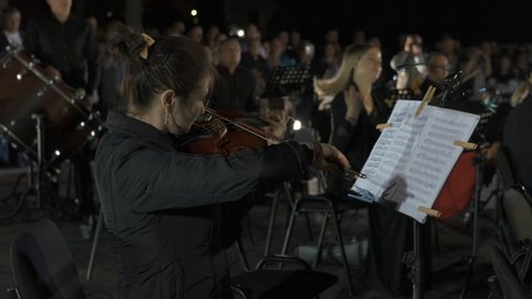 Tiraspol, Moldova - September 2019: Listen violin. Violinist play live classical music in the open night background.