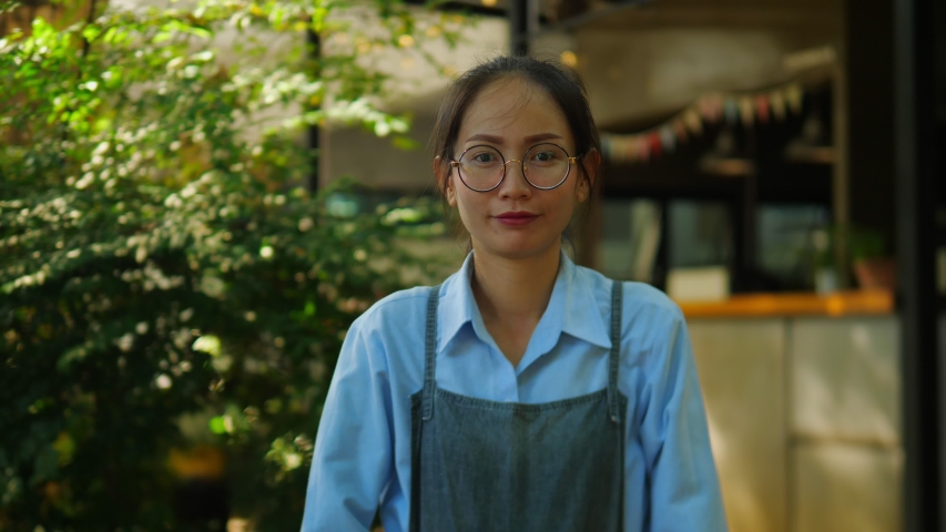 Portrait of Asian woman small business owner standing in her opening coffee shop and smiling looking at camera.