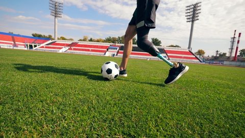 Footballer with a bionic leg is running with a ball