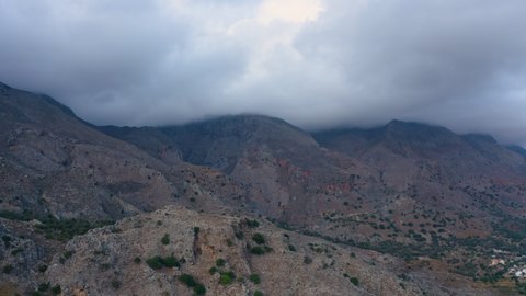 Flying above Mountains in Greece. Aerial view of Stormy clouds cover Mountain. Clouds above gorge 