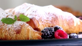 Crunchy fresh croissants raspberries blackberries blueberry and melissa sprinkled with powdered sugar served in a cafe. Video shot 4K 50fps.