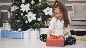 Light 4k video of cute kid sitting with gift in hands, like a little gnome in christmas decorated room.