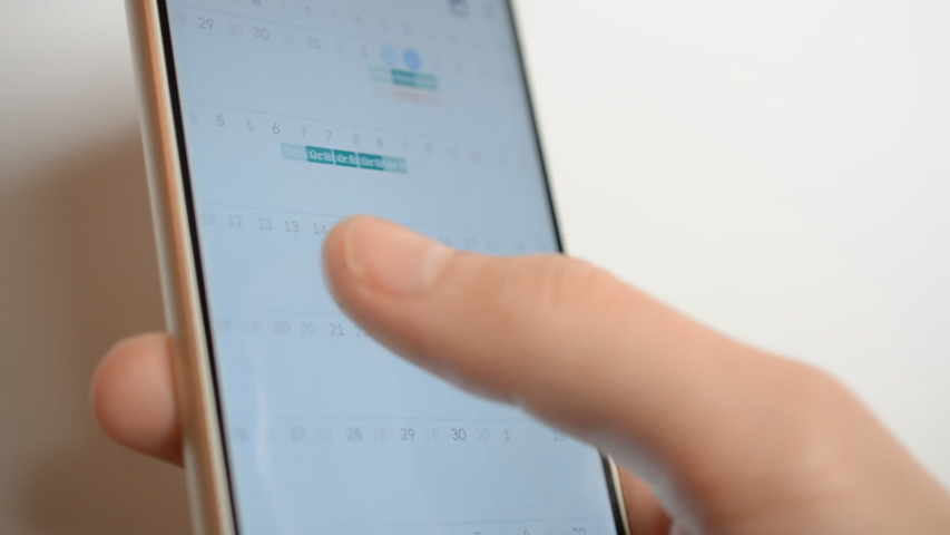 Man using calendar app on the mobile device closeup on white