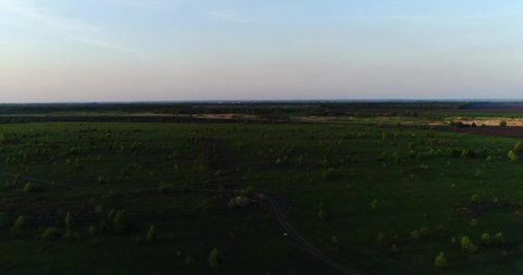 Hang glider flight in sunset time over green and yellow fresh spring fields. Aerial top view. Taken with drone.