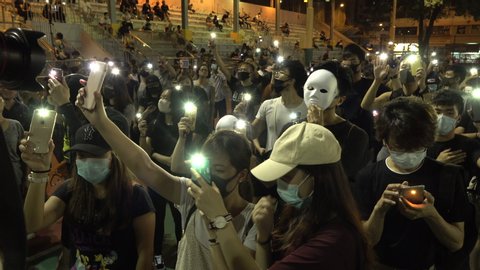 HONG KONG – 5 OCTOBER 2019: Young activists in Hong Kong use smartphone lights while gathering at sports field to protest against face mask ban and various other political and economic issues