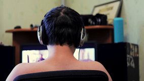 A young guy in headphones sits in front of a computer monitor and watches a video