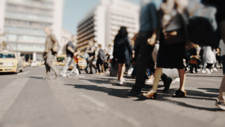 City commuters walking across.Pedestrians and shoppers commuting in the city on a busy bright day crossing the intersection.No logos trademarks or faces visible. Royalty-Free Stock Footage #1040224061