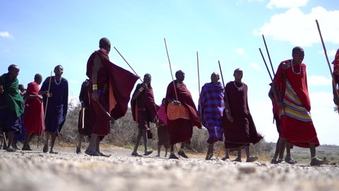 Serengeti / Tanzania - 10 05 2019: Males from African Maasai Tribe Walking and Jumping in Authentic Colorful Clothes, 120fps Slow Motion