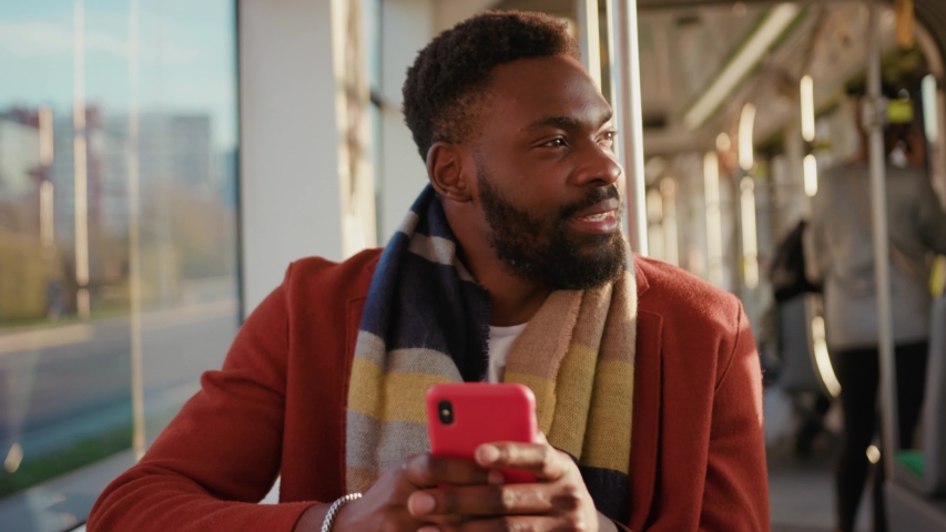 Portrait smiling young african american man use smartphone sitting in tram traffic typing at sunny day handsome passangers stylish transportation using way internet online texting guy slow motion