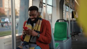 Smiling african american man use smartphone sitting in tram look around traffic typing handsome passangers stylish transportation using way internet online texting guy slow motion