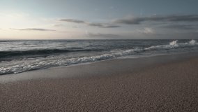 Slow Motion clip of little waves smoothly crashing on the shore of a nice beach of the mediterranean sea with soft sunrise light
