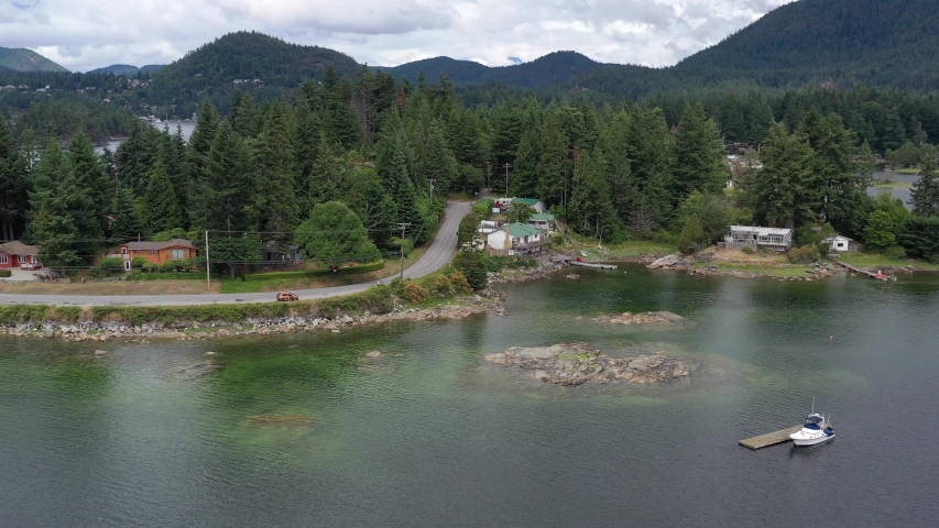 Aerial view over inlet, ocean and island with boat and mountains in beautiful British Columbia. Canada. 4K.
