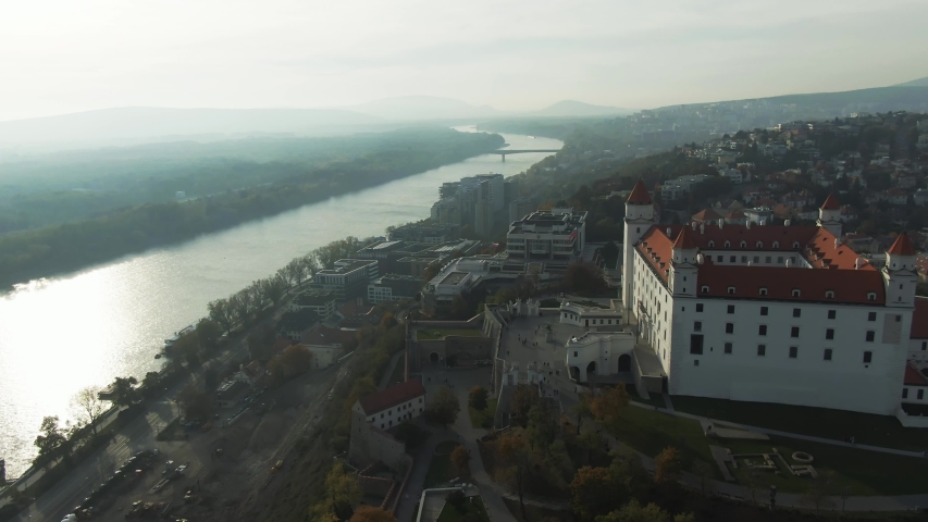 Aerial Tripod Shot of Bratislava Castle and SNP UFO Bridge With Riverside Next to a Danube River During a Foggy Autumn Evening in Bratislava, Slovakia