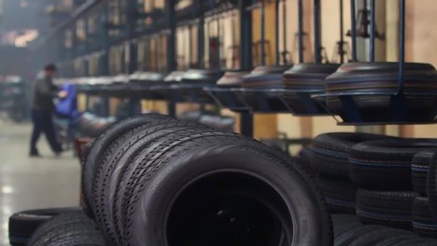 Bila Tserkva, Ukraine - December, 2017: New qualitative black rubber tire with colored marks on deep protector transported by conveyor. Large car tire factory.