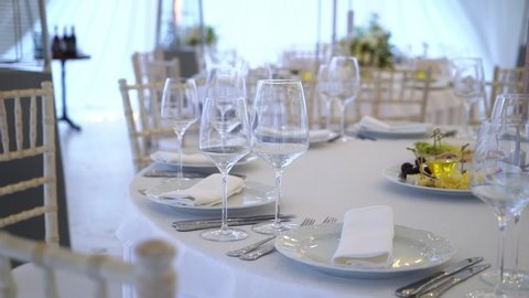 Glasses, plates, Cutlery and napkins. Decorated tables with flowers for the party. Wedding reception, birthday, anniversary