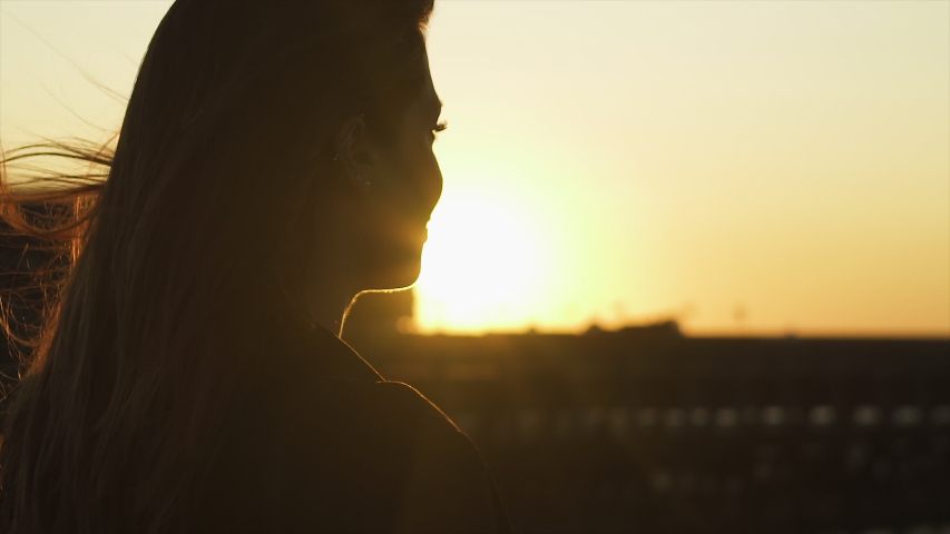 Happy Cute natural redhead woman, freckles, red hair and black jacket posing at Deauville beach, France, during summer sunset. Golden Hour. Wind hair in pontoon 4K UHD close-up back slow motion.
