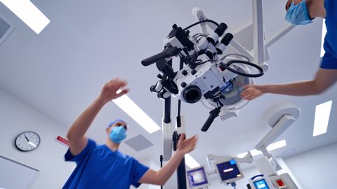 Surgeon with intraoperative microscope. Specialist looking through the medical microscope. Modern equipment in operating room. View from below.
