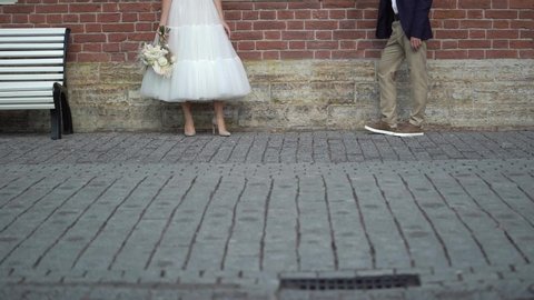 Bride and groom walking in a city. Young lovely wedding couple. Bridal flowers bouquet.